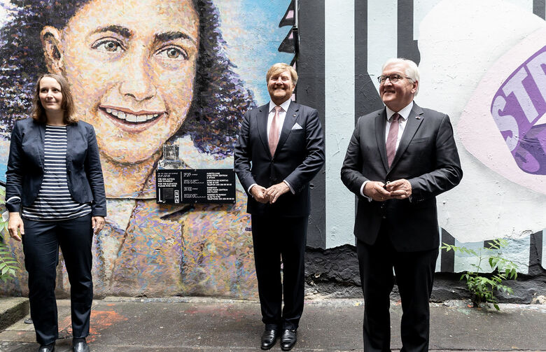 Veronika Nahm, Willem-Alexander der Niederlande und Frank-Walter Steinmeier stehen in Berlin vor einem Graffiti, das Anne Frank zeigt